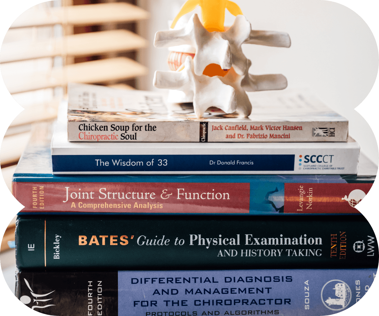Stack of chiropractic textbooks with spine model